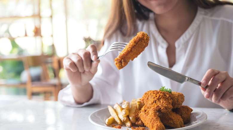 close up of woman eating fried foods and french fries