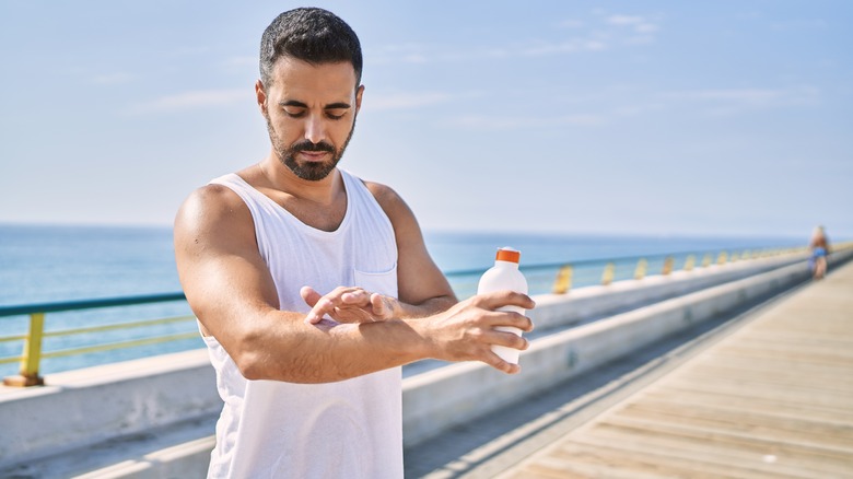 man putting on sunscreen before workout