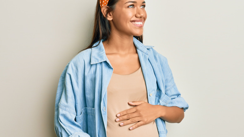 smiling pregnant woman holding belly 