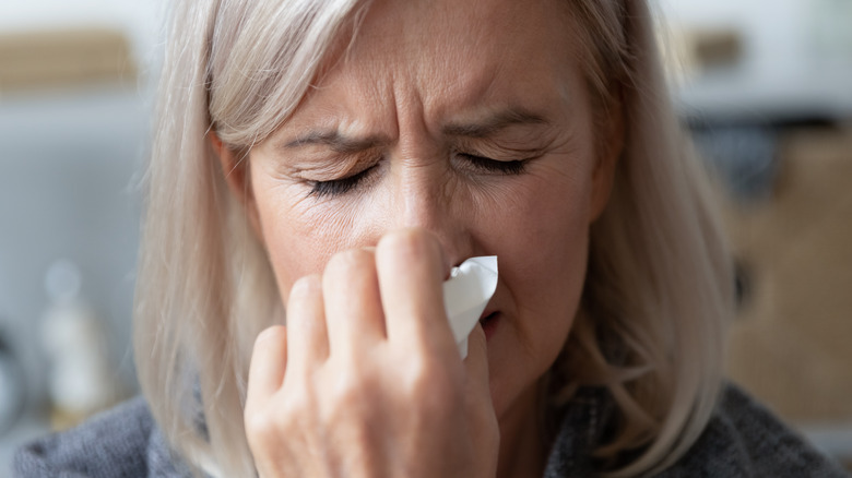 senior female holding a tissue on her nose