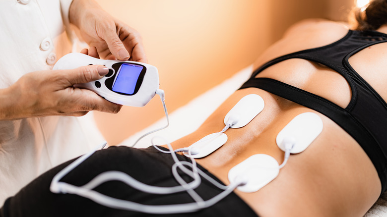 Transcutaneous electrical nerve stimulation (TENS) therapy on woman's back