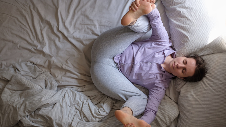 Woman doing happy baby pose in bed