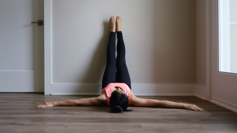 Woman lying on the ground with her legs propped up against the wall