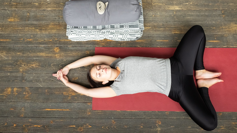 Woman lying on a yoga mat doing supine butterfly pose