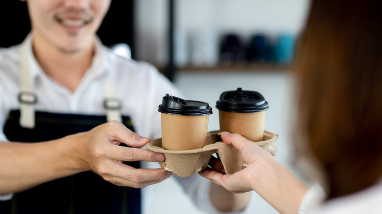 Barista handing woman to-go coffee tray