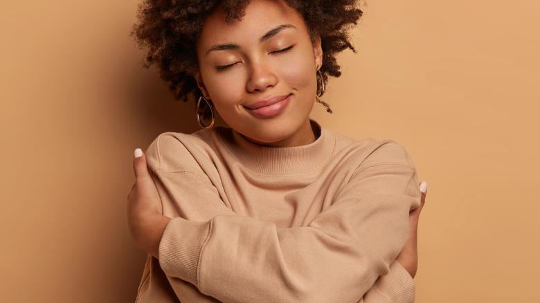 Woman smiling and hugging herself