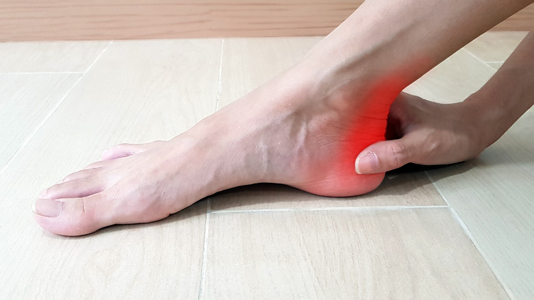 hand touching painful achilles tendon
