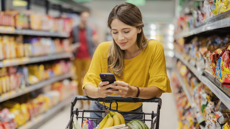 Woman reading shopping list on phone