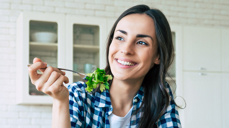 Woman eating a salad with a smile