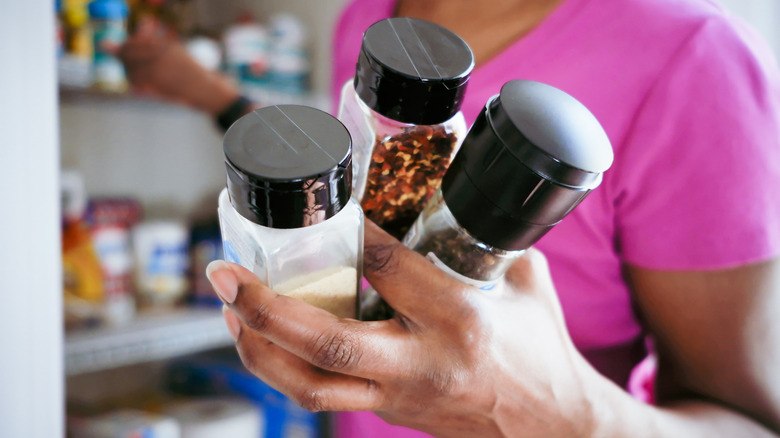 woman holding three different spices in bottles