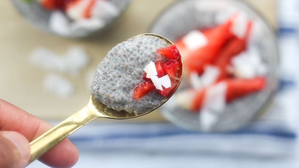 Sliced strawberry and coconut flake on a spoon full of chia seed pudding