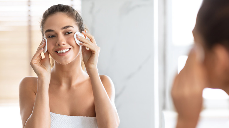 A woman uses cotton pads to clean her face