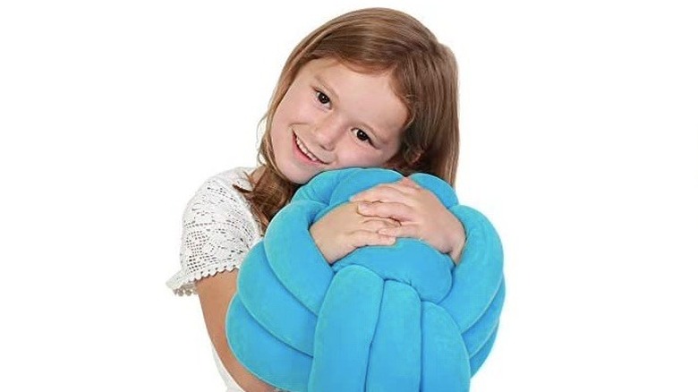 girl cuddling a knot pillow