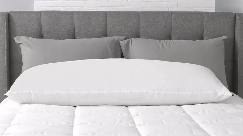 A body pillow lying across a bed