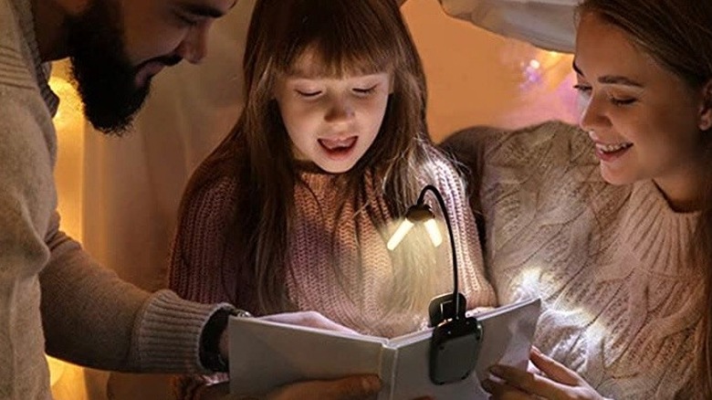 A family reading with a book light