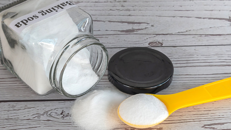 Baking soda on a yellow spoon in wooden background