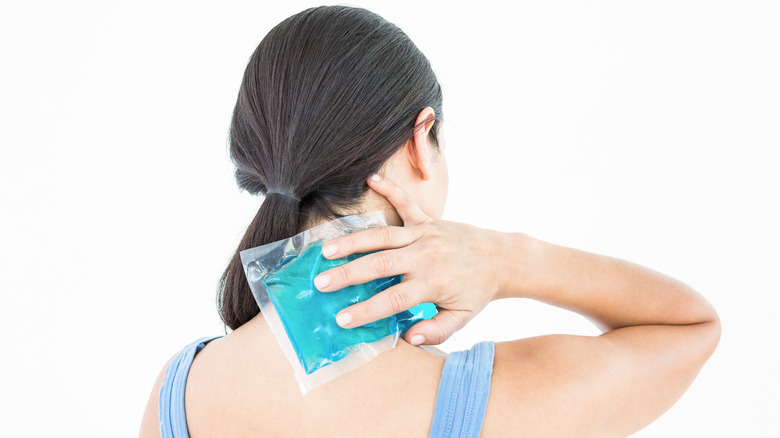 woman holding ice pack on the nape of the neck