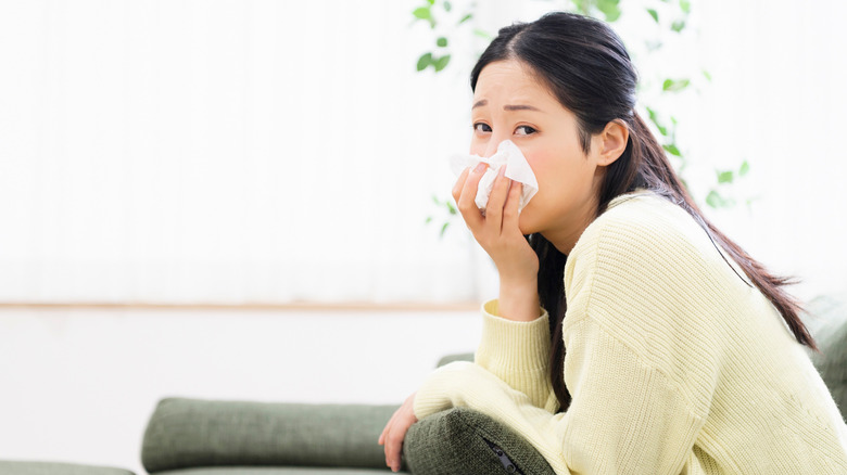 woman leaning forward holding a tissue to her nose