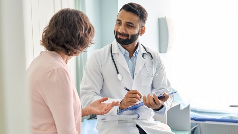 male doctor listening to female senior patient