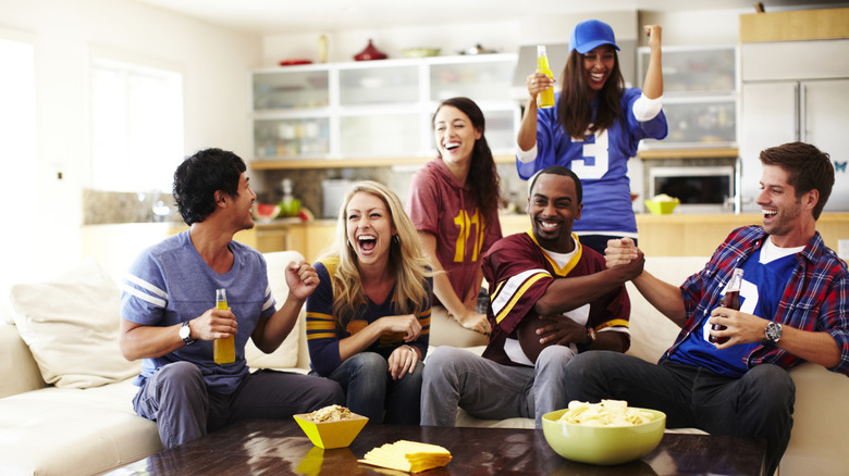 Friends cheering on the couch watching football