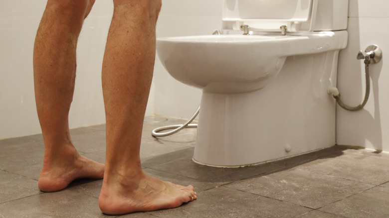 man's legs in front of toilet