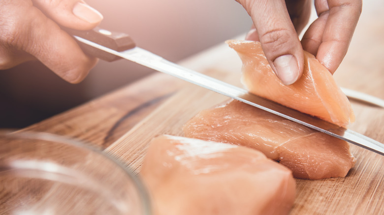 A person cutting up lean chicken