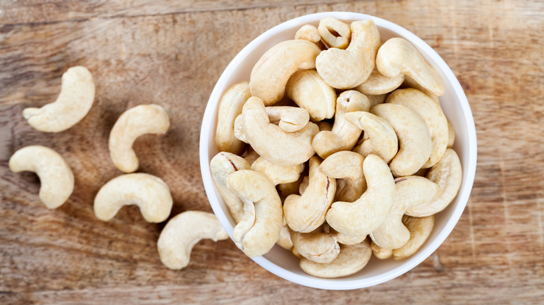 cashew nuts in white bowl and on table
