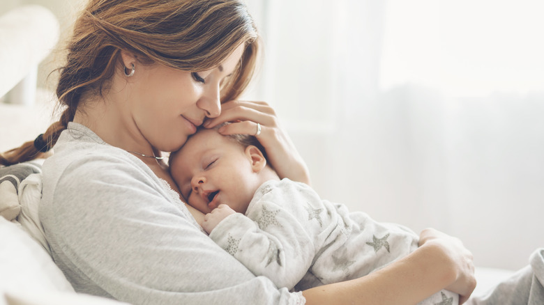 Mother holding her sleeping baby against a white background