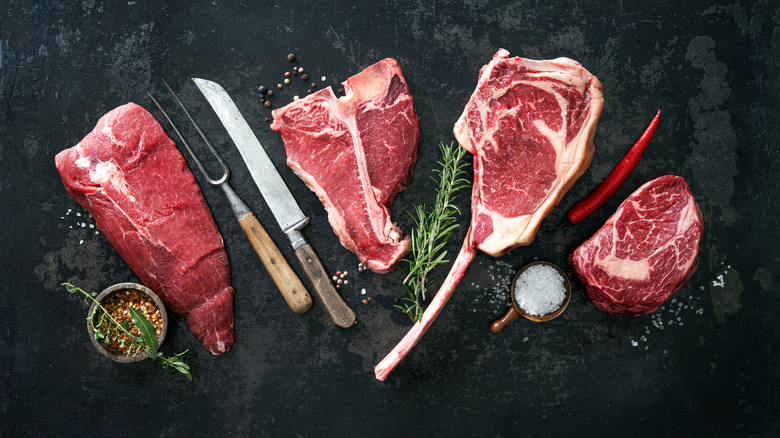 a variety of steaks with knife and seasoning