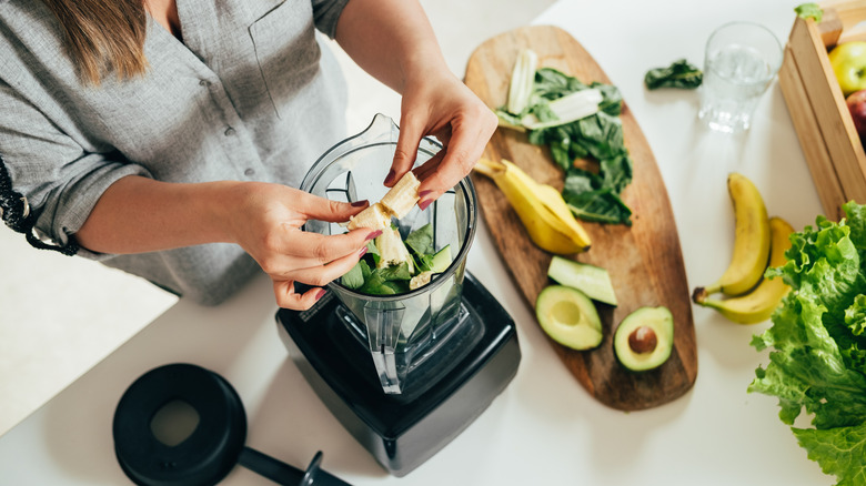 woman preparing smoothie with spinach