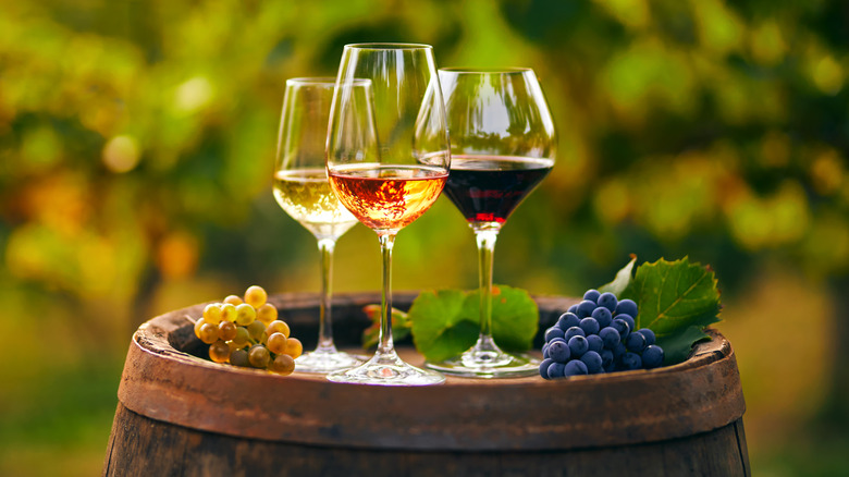 Three glasses of wine sitting on a barrel 