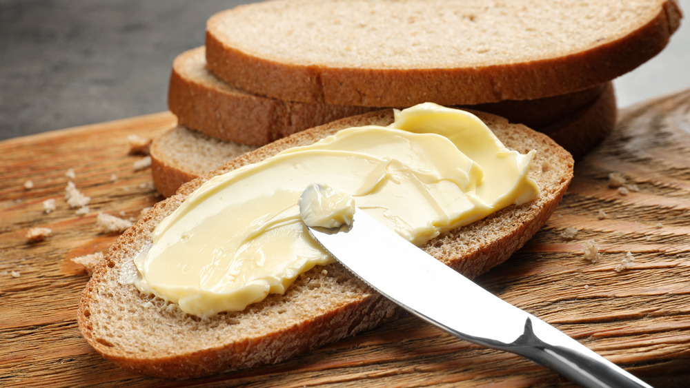 a knife buttering a slice of bread