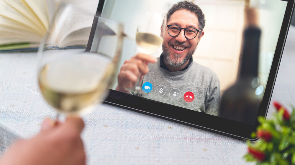 Two people during a Skype call with wine