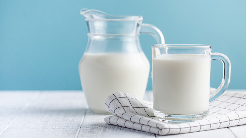 glass of milk with jug behind it