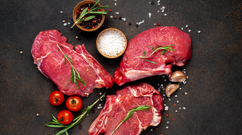 red meat on a black table surrounded by seasoning