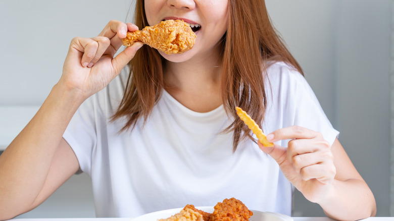 woman eating fried chicken and french fries