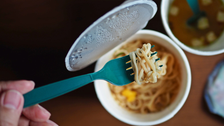 someone eating instant noodles with a disposable fork