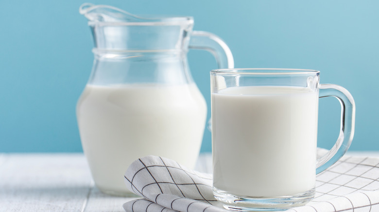 A pitcher of milk by a glass