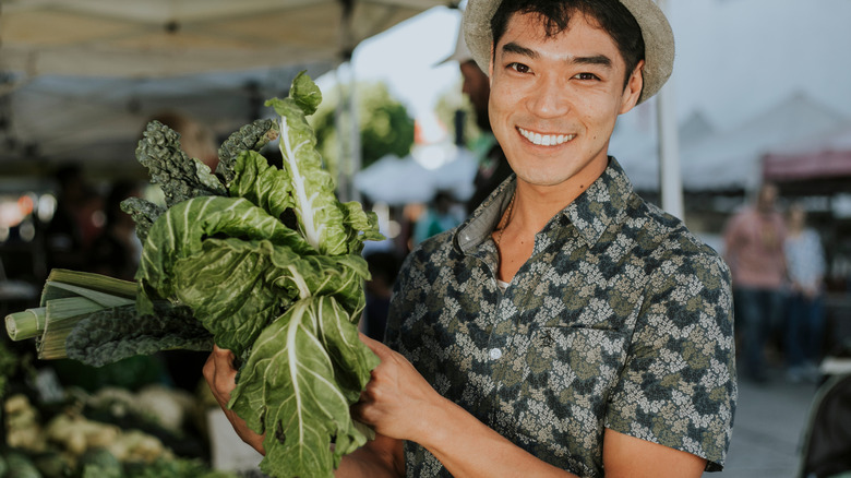 man smiling and holding kale