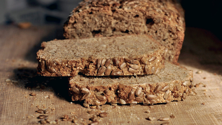 Close up shot of two slices of organic multi whole grain bread stacks in front of a loaf of the same bread