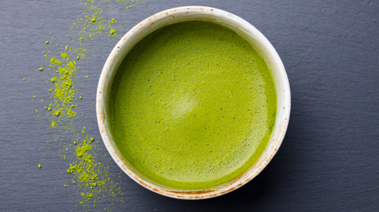 Overhead shot of green tea in a chawan cup next to powdered green tea