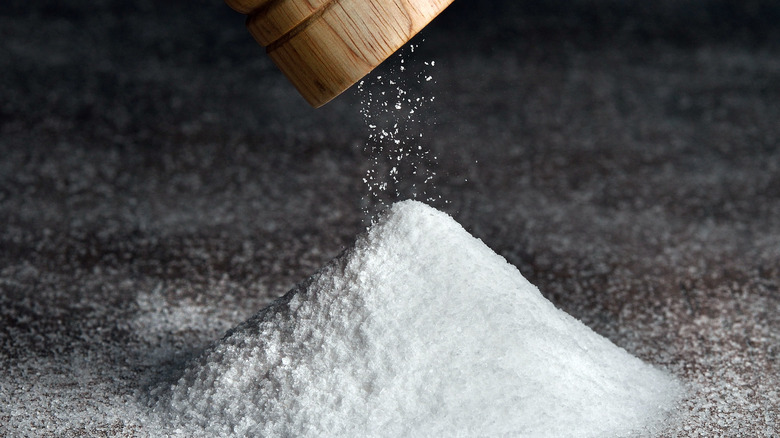 Salt shaker poring salt in a pile 