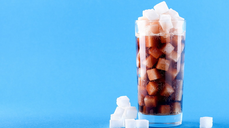 A glass of soda filled with sugar cubes