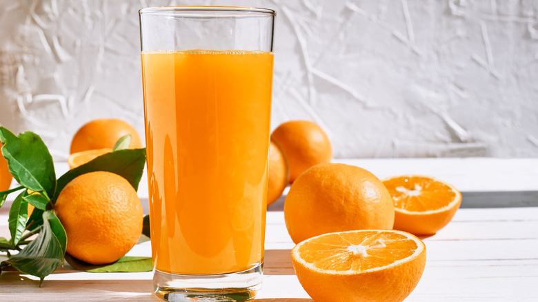 A glass of orange juice and oranges