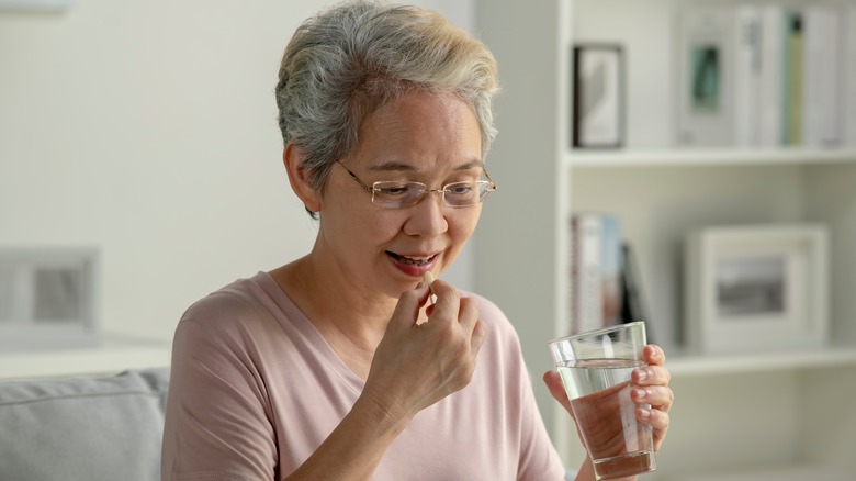 Asian woman taking medication at home