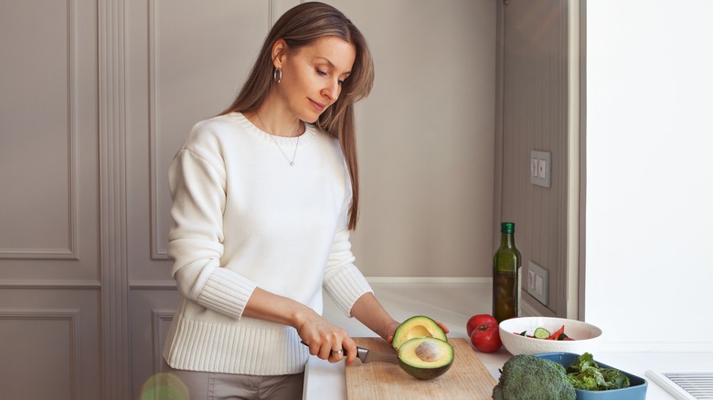 Woman cutting an avocado in her kitchen