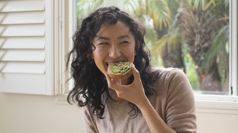 Woman smiling while eating avocado toast