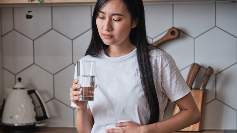 Woman clutching her stomach in the kitchen