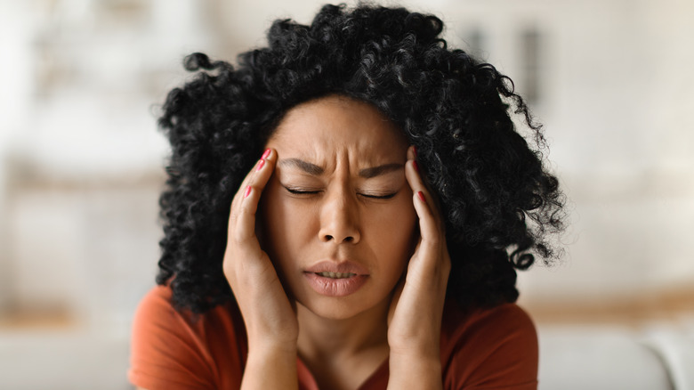 Woman with a migraine clutching her head