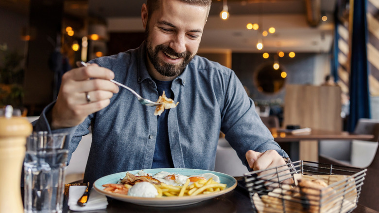 A happy man eating eggs at a restaurant